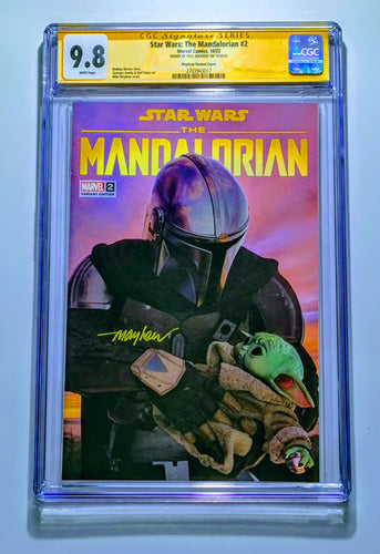 A trading card featuring an image of a character from Star Wars, specifically The Mandalorian, holding a small character, with a purple and orange backdrop. The card is signed by Meyhew and has a CGC SS label.
